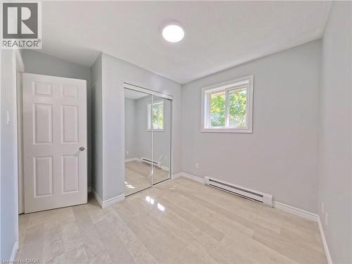 Bedroom featuring light grey walls, light wood-finish flooring, a contemporary ceiling light fixture, and a window with white trim - 119 Cedar Street S Unit# 14, Kitchener, ON - Indoor Photo Showing Other Room