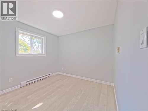 Room featuring light-toned wood-finish flooring, a white trim baseboard, and a round ceiling light fixture - 119 Cedar Street S Unit# 14, Kitchener, ON - Indoor Photo Showing Other Room