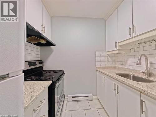 Contemporary kitchen featuring white cabinetry, subway tile backsplash, granite-finish countertops, stainless steel sink with a pull-down faucet, and a black range with an overhead hood - 119 Cedar Street S Unit# 14, Kitchener, ON - Indoor Photo Showing Kitchen