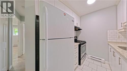 Compact kitchen featuring white cabinetry, a white refrigerator, and a stainless steel oven - 119 Cedar Street S Unit# 14, Kitchener, ON - Indoor Photo Showing Kitchen