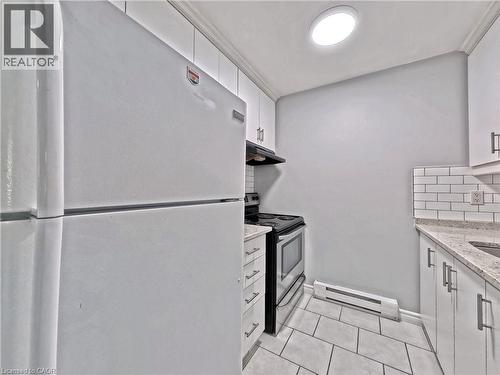 Kitchen featuring white appliances, white subway tile backsplash, white cabinetry with contemporary pulls, granite-style countertops, and a tile floor - 119 Cedar Street S Unit# 14, Kitchener, ON - Indoor Photo Showing Kitchen