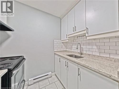Kitchen featuring white shaker-style cabinetry, a stainless steel sink with a gooseneck faucet, light-toned speckled countertops, and a white subway tile backsplash - 119 Cedar Street S Unit# 14, Kitchener, ON - Indoor Photo Showing Kitchen