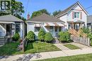 White siding exterior with a shingled roof, featuring a front porch with a striped awning - 155 Newlands Avenue, Hamilton, ON  - Outdoor 