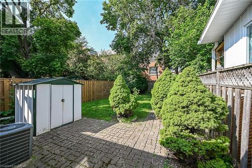 Paved patio area featuring a metal storage shed, a manicured lawn, and natural wood fencing - 155 Newlands Avenue, Hamilton, ON - Outdoor