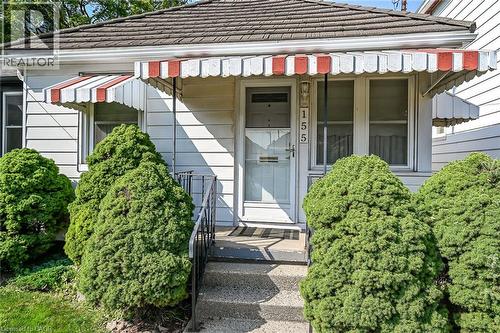 White siding exterior featuring a red and white striped awning over the front entry - 155 Newlands Avenue, Hamilton, ON - Outdoor