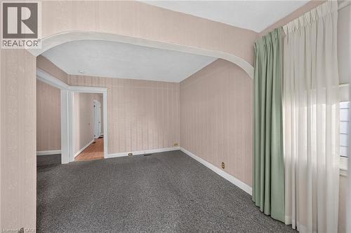 Room featuring an arched entryway, textured wallpaper, carpeting, baseboard molding, and a window with sheer and opaque drapes - 155 Newlands Avenue, Hamilton, ON - Indoor Photo Showing Other Room