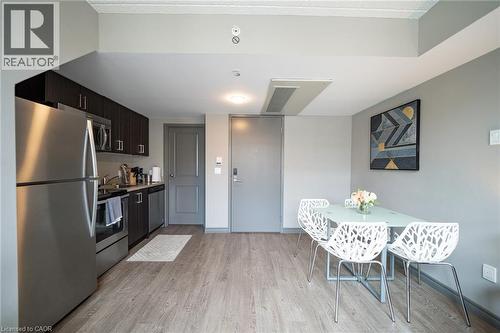 Modern kitchen featuring stainless steel appliances, dark wood-finish cabinetry, and wood-finish flooring - 321 Spruce Street Unit# 710, Waterloo, ON - Indoor