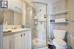 Bathroom featuring a walk-in shower with glass enclosure, white vanity with stone-finish countertop, and a built-in mirror - 