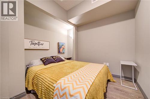 Recessed sleeping area with light neutral wall tones, wood-finish flooring, and a low profile baseboard trim - 321 Spruce Street Unit# 710, Waterloo, ON - Indoor Photo Showing Bedroom