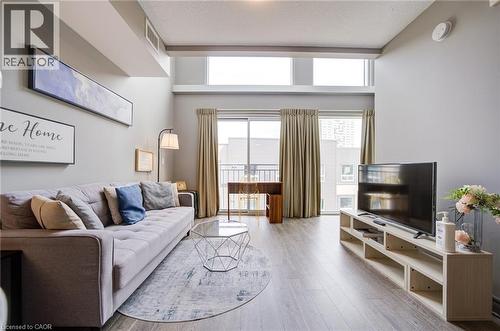 Living area featuring high ceilings, wood-finish flooring, and a sliding glass door to a balcony - 321 Spruce Street Unit# 710, Waterloo, ON - Indoor Photo Showing Living Room