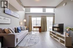 Living area featuring high ceilings, wood-finish flooring, and a sliding glass door to a balcony - 