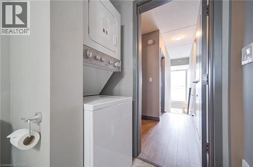 Stacked laundry unit with white appliances, set within a neutral-toned interior - 321 Spruce Street Unit# 710, Waterloo, ON - Indoor Photo Showing Laundry Room