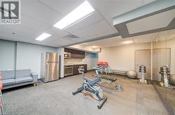 Fitness area featuring mirror wall, recessed lighting, and a kitchenette with stainless steel appliances - 