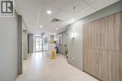 Modern entryway featuring double glass doors, recessed lighting, grid acoustic ceiling, and wood-finish cabinetry - 