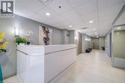 Bright reception area featuring a white, contemporary desk, recessed lighting, and light-toned floor tiling - 