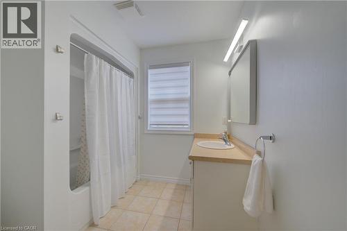 Bathroom featuring a shower-tub combination, single vanity with a laminate countertop, a framed mirror, and tile flooring - 729 Keats Way, Waterloo, ON - Indoor Photo Showing Bathroom