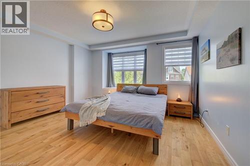 Spacious room featuring light wood-finish flooring and two large windows with blinds - 729 Keats Way, Waterloo, ON - Indoor Photo Showing Bedroom