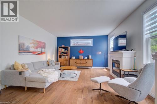 Bright living area featuring wood-finish flooring, a prominent white mantelpiece with an integrated fireplace, and windows with horizontal blinds - 729 Keats Way, Waterloo, ON - Indoor Photo Showing Living Room With Fireplace