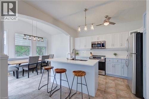 Kitchen featuring white upper cabinetry, light blue lower cabinetry, stainless steel appliances, a white subway tile backsplash, and an island with a white countertop - 729 Keats Way, Waterloo, ON - Indoor Photo Showing Kitchen
