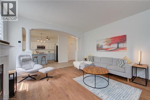 Open-concept living space featuring wood-finish flooring, white walls, an arched entryway, and a fireplace mantel - 729 Keats Way, Waterloo, ON - Indoor Photo Showing Living Room