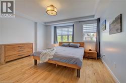 Spacious room featuring light wood-finish flooring and two large windows with blinds - 