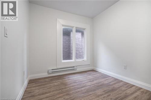 Room featuring wood-finish flooring, white walls, white baseboards, and a window with white trim - 524 King Street E Unit# 3, Hamilton, ON - Indoor Photo Showing Other Room