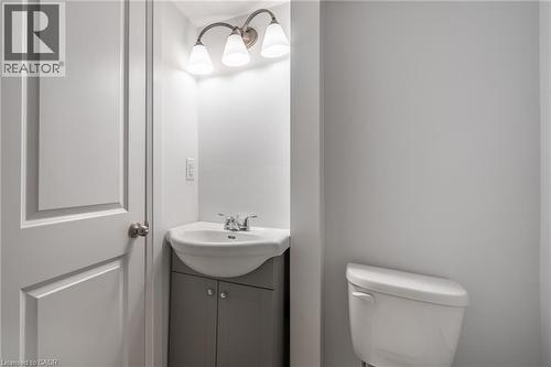 Powder room featuring a corner vanity with a white ceramic sink, brushed nickel faucet, and a three-light vanity fixture - 524 King Street E Unit# 3, Hamilton, ON - Indoor Photo Showing Bathroom