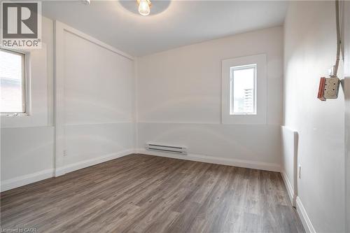 Open room featuring wood-finish flooring, white walls, and two windows providing natural light - 524 King Street E Unit# 3, Hamilton, ON - Indoor Photo Showing Other Room