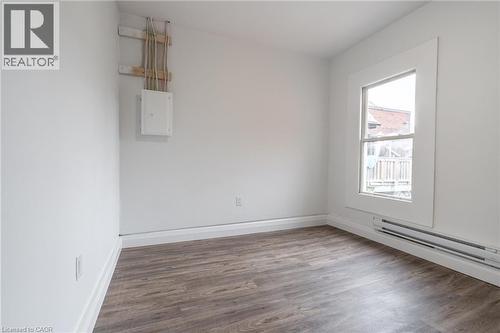 Bright interior space featuring wood-finish flooring, white baseboards, and a large window with white trim - 524 King Street E Unit# 3, Hamilton, ON - Indoor Photo Showing Other Room