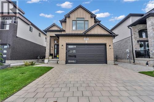 Contemporary two-story residence featuring a light brick facade and dark trim accents - 2195 Ironwood Road, London, ON - Outdoor