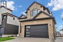 Contemporary exterior featuring a two-car garage with frosted glass inserts, light brick facade, and dark roofline - 2195 Ironwood Road, London, ON  - Outdoor 