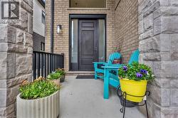 Front entry featuring a dark-paneled door with sidelight, brick facade, and stone column accents - 