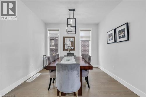 Contemporary dining area featuring wood-finish flooring, a modern linear chandelier, recessed lighting, and white baseboards - 2195 Ironwood Road, London, ON - Indoor Photo Showing Dining Room