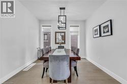 Contemporary dining area featuring wood-finish flooring, a modern linear chandelier, recessed lighting, and white baseboards - 
