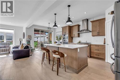 Modern kitchen featuring a central island with white countertop, warm wood cabinetry, stainless steel appliances, and a subway tile backsplash - 2195 Ironwood Road, London, ON - Indoor Photo Showing Kitchen With Stainless Steel Kitchen With Upgraded Kitchen