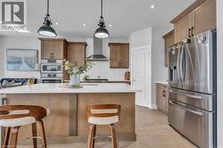 Kitchen featuring light wood-finish cabinetry, stainless steel appliances, a white subway tile backsplash, and a large island with a light-toned countertop - 