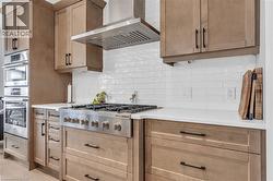 Stainless steel range with a coordinating hood, surrounded by light wood-finish cabinetry - 