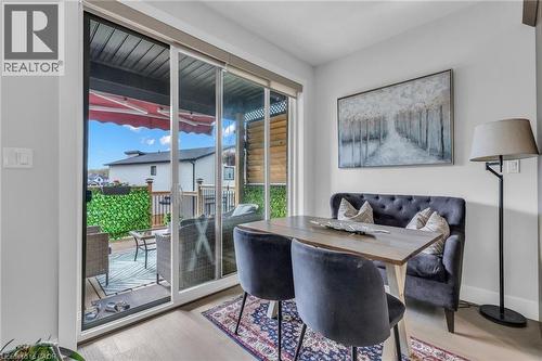 Sliding glass patio door opening to an outdoor living space with a wood deck and artificial foliage privacy screen - 2195 Ironwood Road, London, ON - Indoor