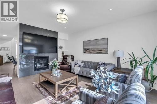Spacious living area featuring light wood-finish flooring, a contemporary fireplace with a dark tile surround, and recessed lighting - 2195 Ironwood Road, London, ON - Indoor Photo Showing Living Room With Fireplace