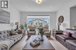 Spacious living area featuring light wood-finish flooring, a large window, recessed lighting, and a prominent ceiling fixture - 