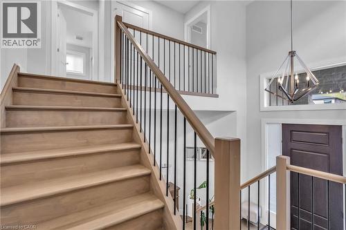 Light wood-finish staircase with black metal balusters and a wood handrail - 2195 Ironwood Road, London, ON - Indoor Photo Showing Other Room