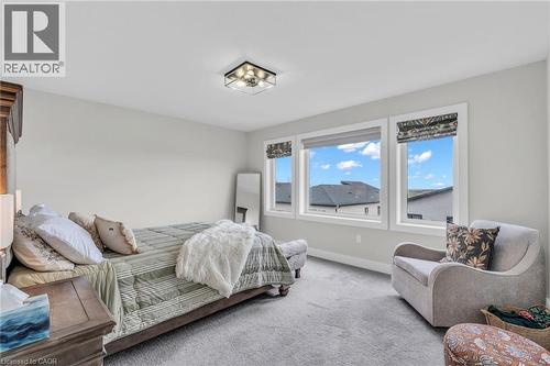 Carpeted room featuring a trio of windows, a flush-mount ceiling light fixture, and light gray walls - 2195 Ironwood Road, London, ON - Indoor Photo Showing Bedroom
