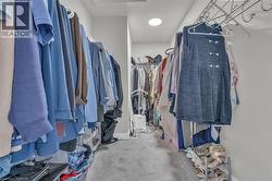 Walk-in closet with carpet flooring, recessed ceiling lighting, and multiple shelving and hanging storage systems - 
