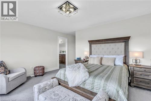 Carpeted sleeping area featuring a wood-frame bed with an upholstered headboard, recessed lighting, and a doorway to an additional room - 2195 Ironwood Road, London, ON - Indoor Photo Showing Bedroom