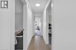 Modern hallway featuring wide-plank wood-finish flooring, white walls, and recessed lighting - 