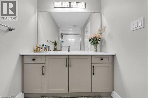 Bathroom vanity featuring a light-toned countertop, integrated sink, and contemporary gray cabinetry with black hardware - 2195 Ironwood Road, London, ON - Indoor Photo Showing Bathroom