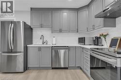 Kitchen featuring light gray cabinetry, stainless steel appliances, white countertops, and a white subway tile backsplash - 