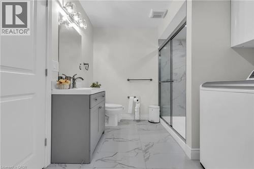 Contemporary bathroom featuring a grey vanity with an integrated sink, a glass-enclosed shower with marble-look wall tiling, a toilet, and large-format marble-look floor tiles - 2195 Ironwood Road, London, ON - Indoor Photo Showing Other Room