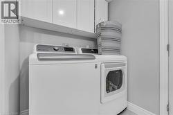 Dedicated laundry area featuring overhead cabinetry for storage and light gray wall paint - 