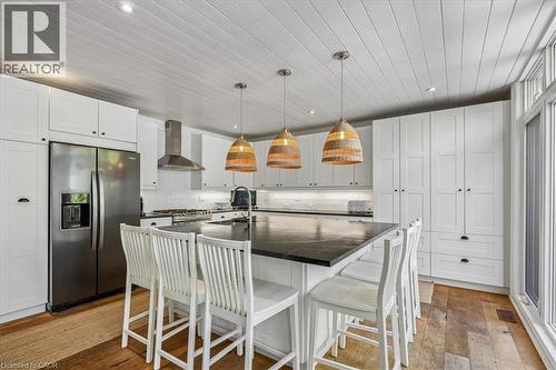 Kitchen featuring a large central island with seating, white shaker-style cabinetry, wood-finish flooring, and a stainless steel side-by-side refrigerator - 573 Beach Boulevard, Hamilton, ON - Indoor Photo Showing Kitchen With Upgraded Kitchen